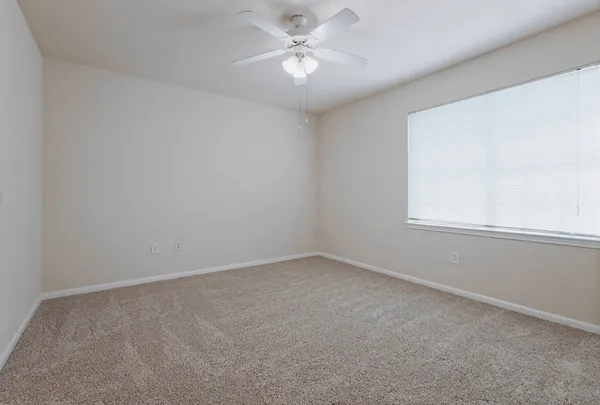 an empty room with a window and a fan