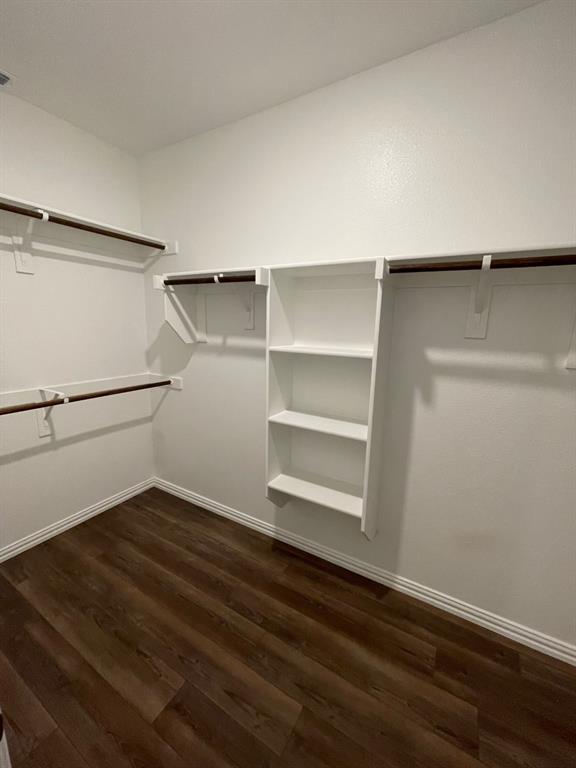 3700 Milkweed Road McKinney, TX 75071 - Photo 12 of 18 Spacious closet featuring wood-finish flooring, white walls, built-in shelving, and multiple hanging rods