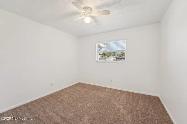 an empty room with a window and a ceiling fan