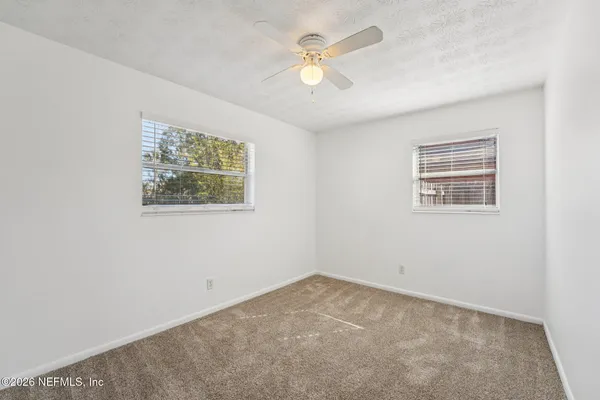 an empty room with a window and a ceiling fan
