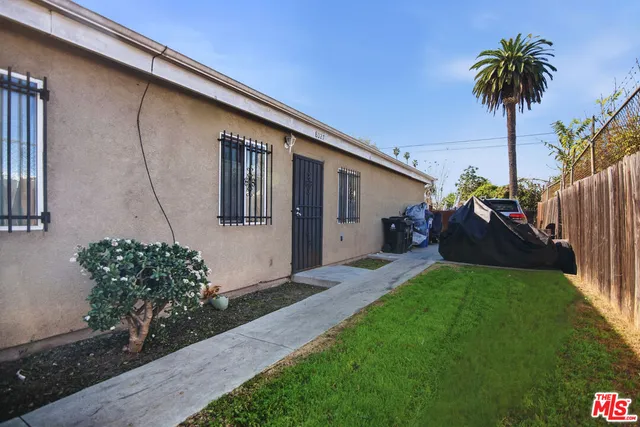 a view of a house with a small yard plants and palm trees