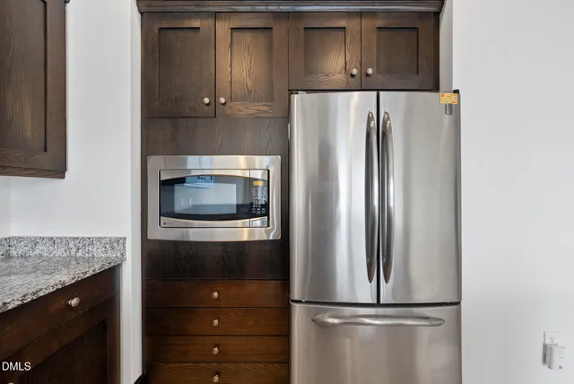 a view of kitchen with stainless steel appliances kitchen island granite countertop refrigerator stove and microwave
