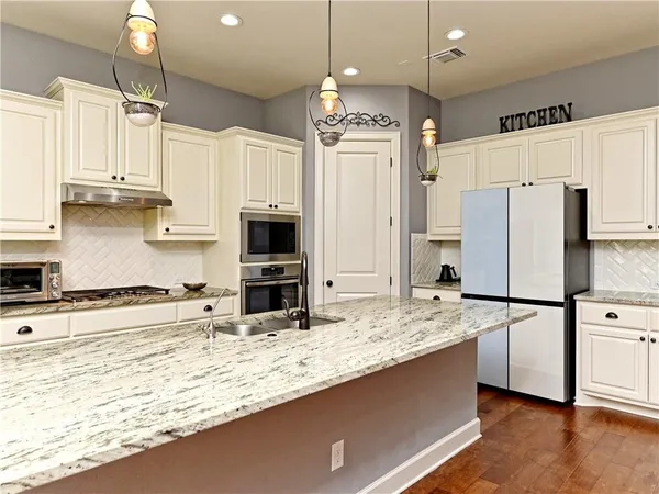 a kitchen with stainless steel appliances granite countertop a sink refrigerator and cabinets