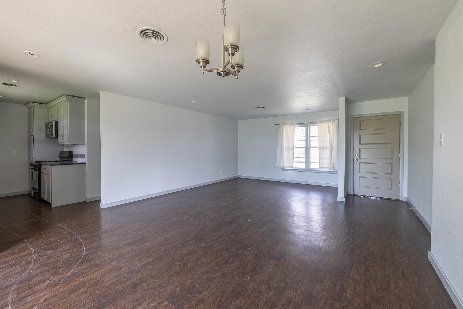 5403 13th Street Lubbock, TX 79416 - Photo 4 of 28 a view of an empty room with wooden floor and a kitchen