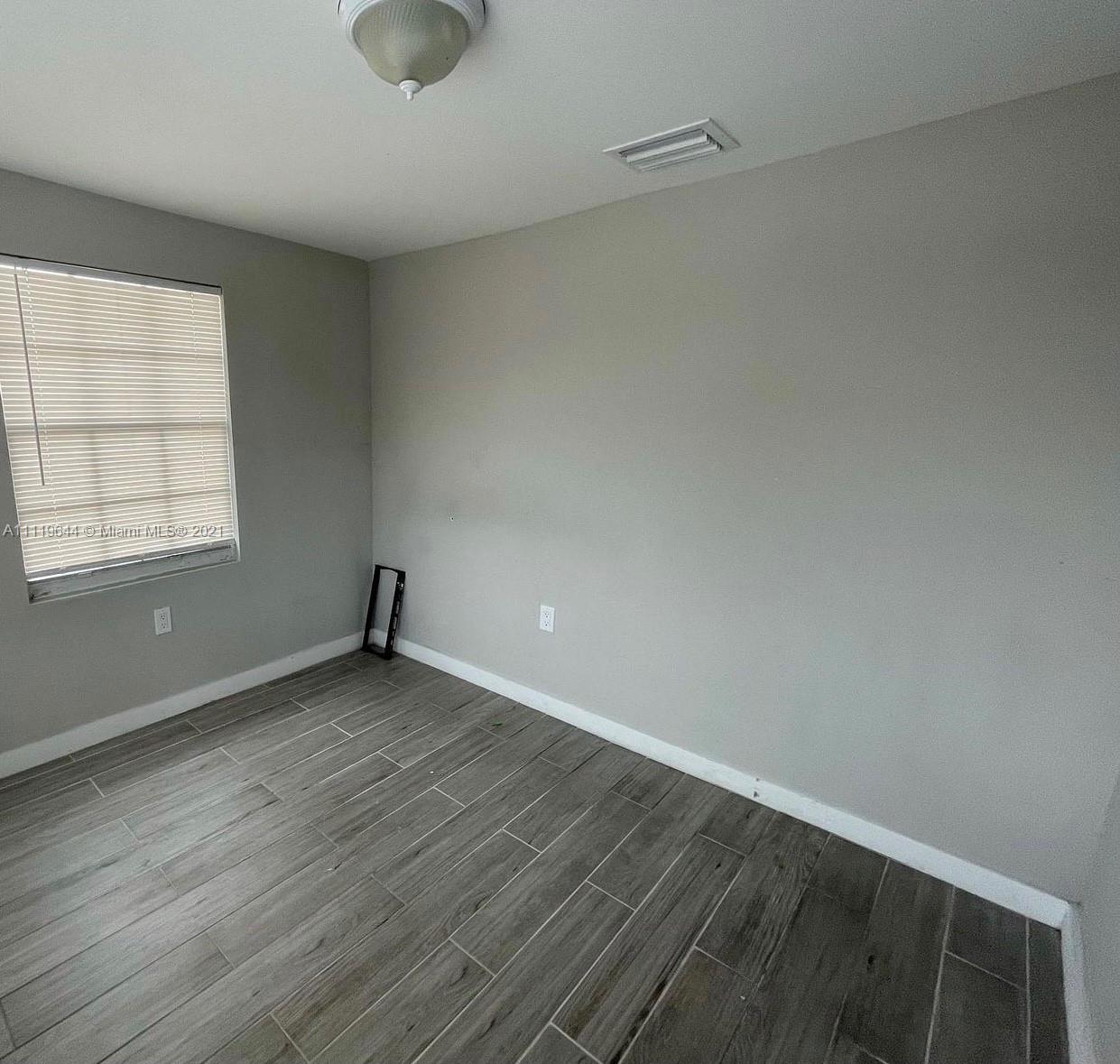 1035 Northwest 5th Street, Unit 3 Miami, FL 33128 - Photo 2 of 6 an empty room with wooden floor and windows