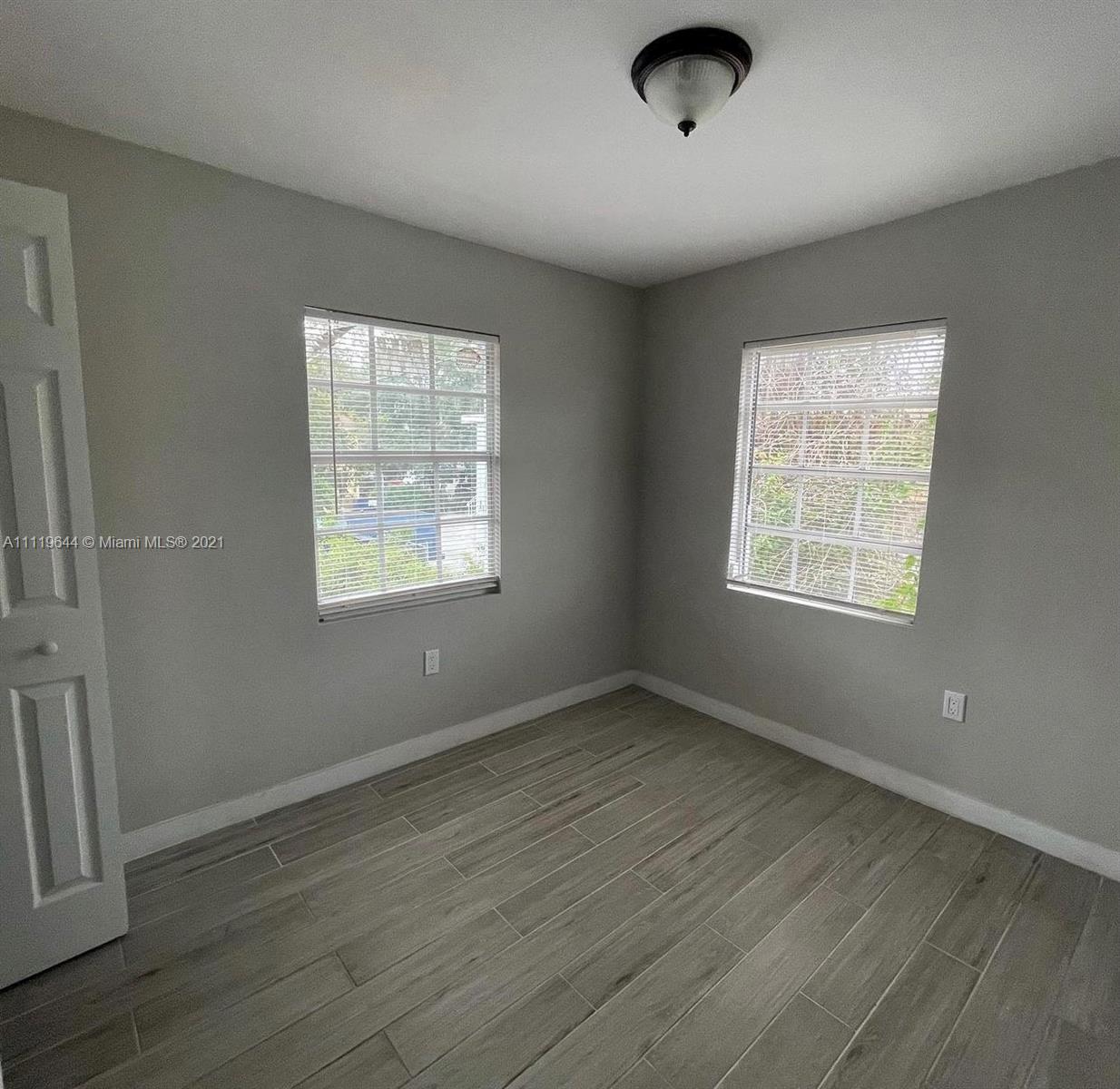 1035 Northwest 5th Street, Unit 3 Miami, FL 33128 - Photo 3 of 6 a view of an empty room with wooden floor and a window