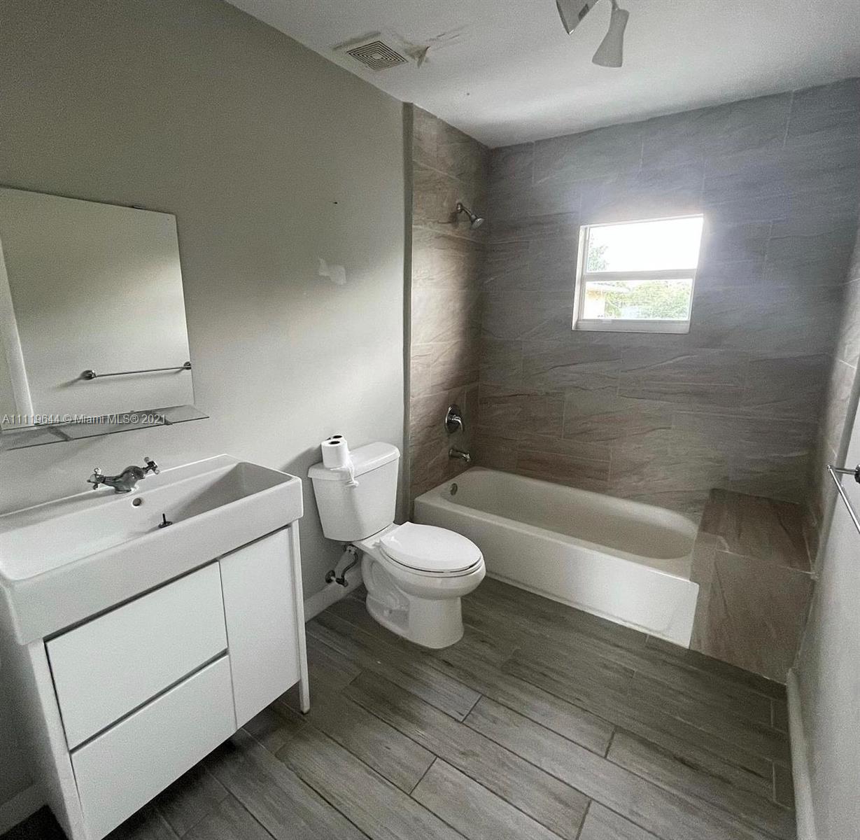 1035 Northwest 5th Street, Unit 3 Miami, FL 33128 - Photo 5 of 6 a bathroom with a granite countertop toilet a sink and a bathtub