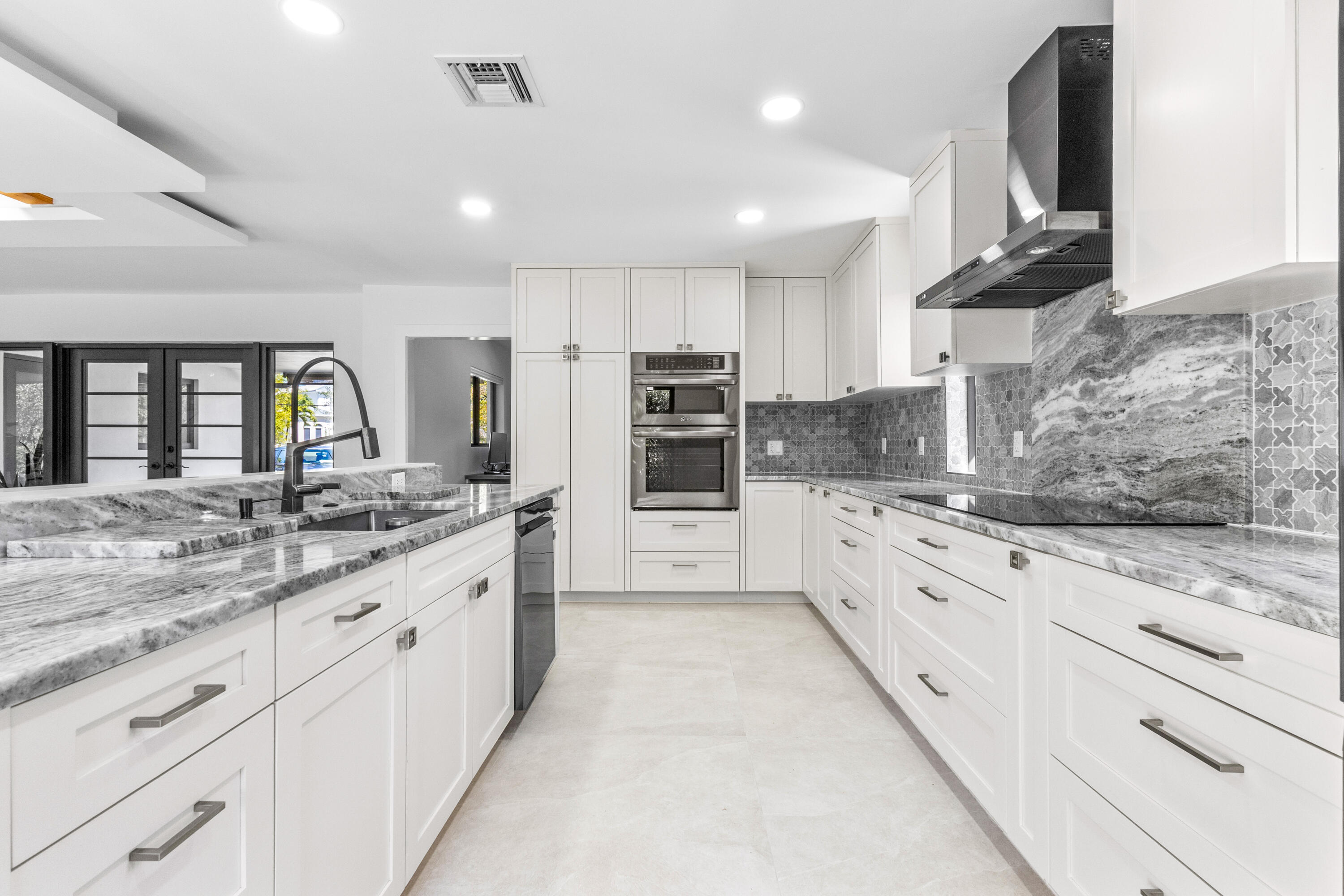 501 High Street Boca Raton, FL 33432 - Photo 4 of 27 a large white kitchen with stainless steel appliances kitchen island granite countertop a large counter top and a stove