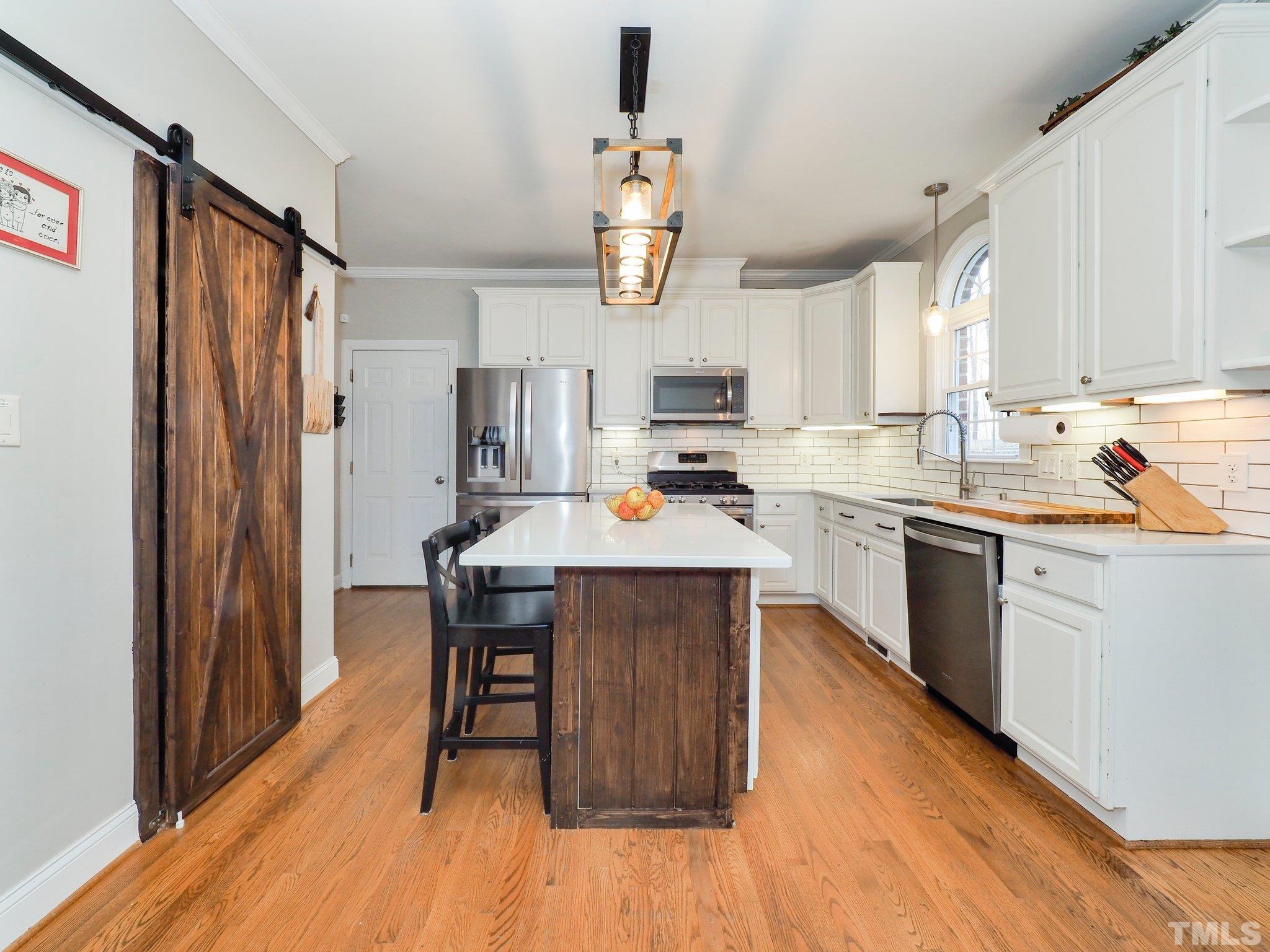 4412 Black Lion Way Raleigh, NC 27610 - Photo 14 of 32 a kitchen with a refrigerator a sink dishwasher a stove and white cabinets with wooden floor