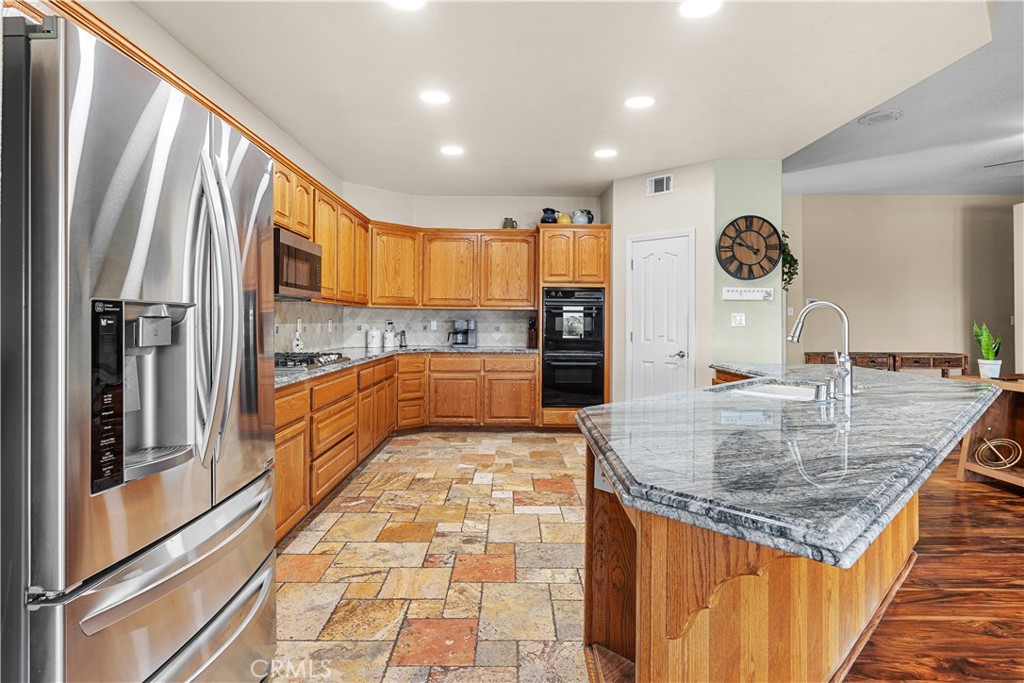 17492 Mariposa Avenue Riverside, CA 92504 - Photo 15 of 43 a kitchen with kitchen island granite countertop a refrigerator a stove and a sink with wooden floor