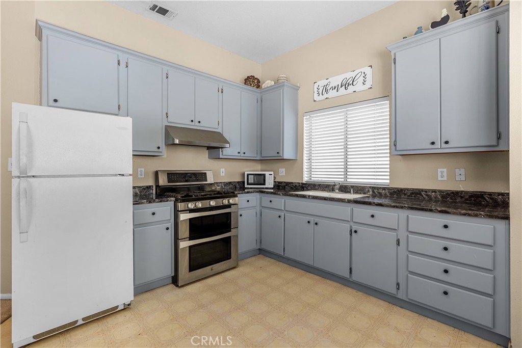 17492 Mariposa Avenue Riverside, CA 92504 - Photo 38 of 43 a kitchen with granite countertop white cabinets and refrigerator