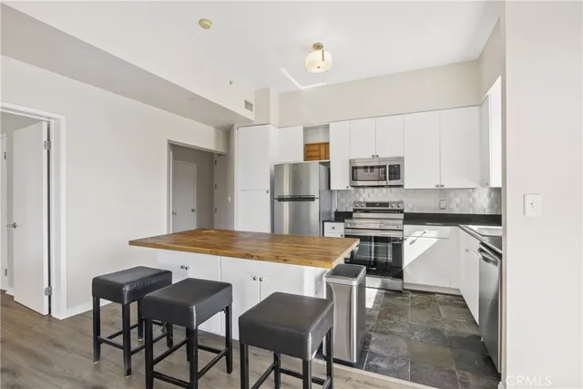 a kitchen with stainless steel appliances kitchen island granite countertop a table chairs microwave and sink