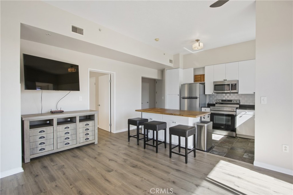 388 East Ocean Boulevard, Unit 302 Long Beach, CA 90802 - Photo 8 of 20 a kitchen with stainless steel appliances a stove a sink dishwasher a refrigerator and a dining table with wooden floor