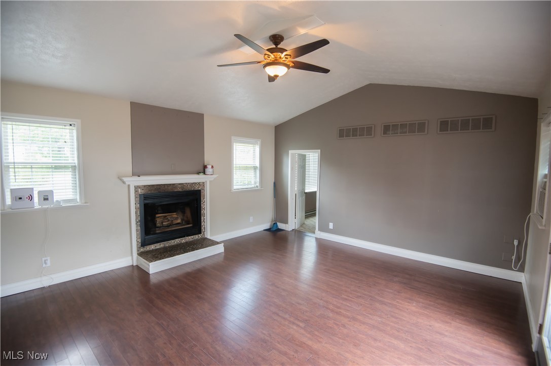 4594 Center Road Andover, OH 44003 - Photo 13 of 39 Unfurnished living room featuring lofted ceiling, dark wood-style flooring, a premium fireplace, and ceiling fan