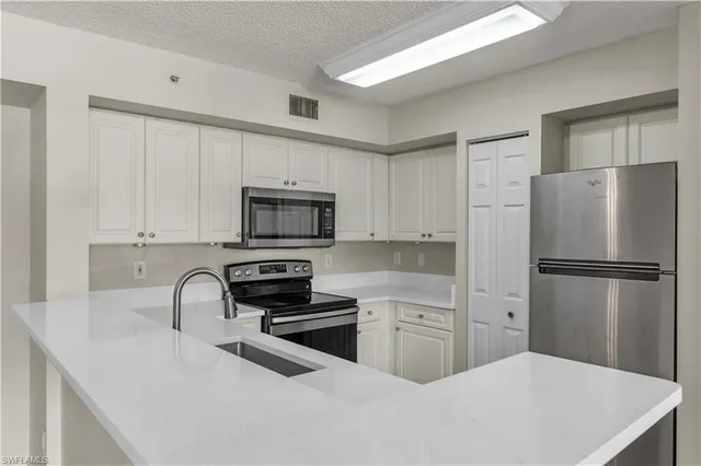 a kitchen with white cabinets and stainless steel appliances