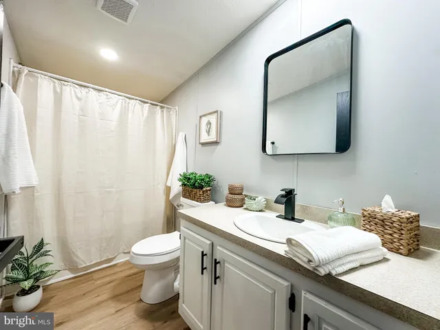 a bathroom with a granite countertop sink vanity mirror and toilet