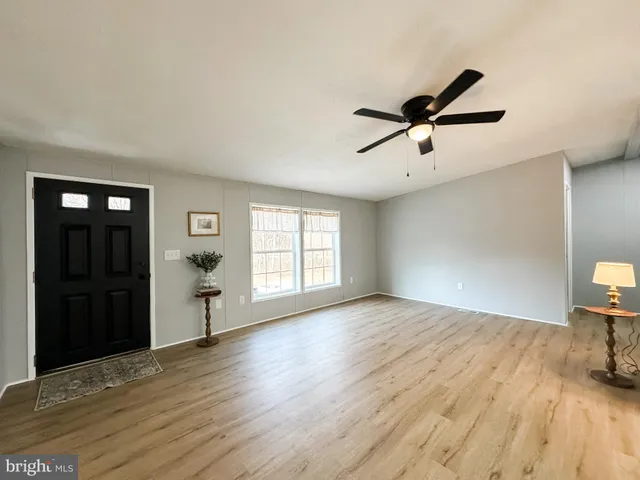 a view of empty room with wooden floor and fan