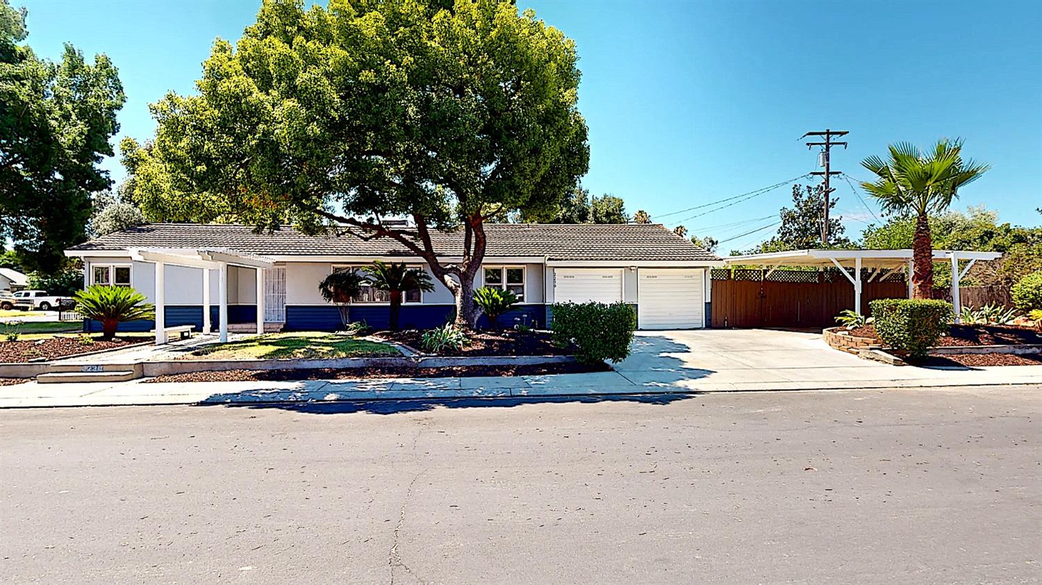 a view of a white house with a large tree next to a yard