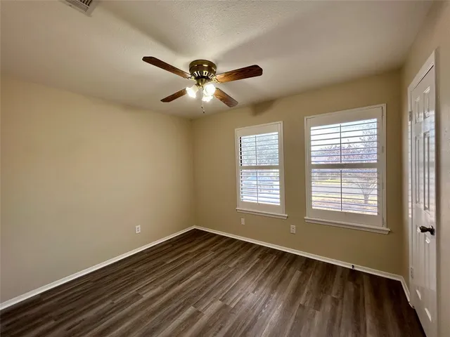 a view of empty room with wooden floor and fan