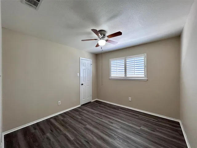 a view of a room with wooden floor and a ceiling fan