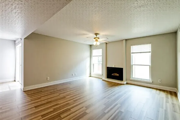 an empty room with wooden floor fireplace and windows