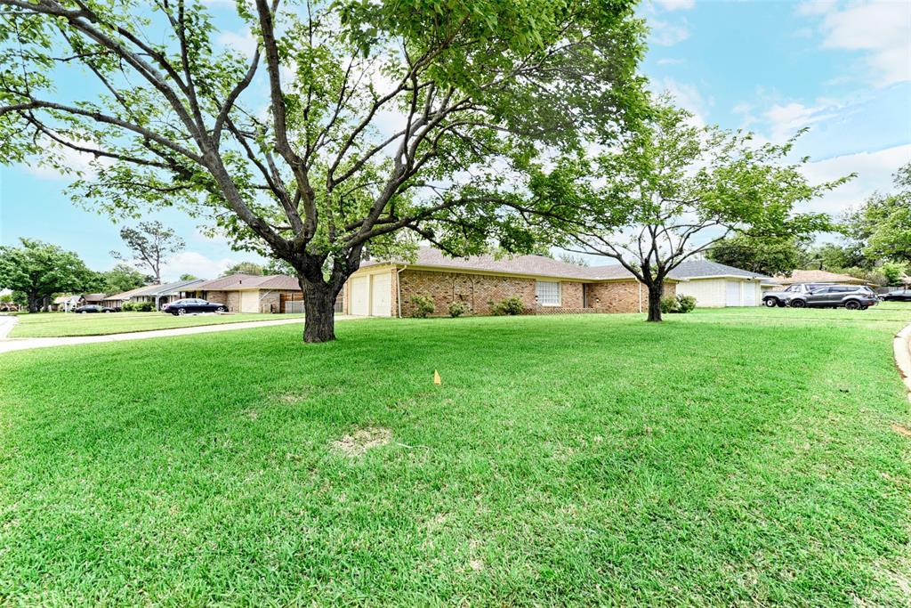 a view of a house with a big yard and large trees