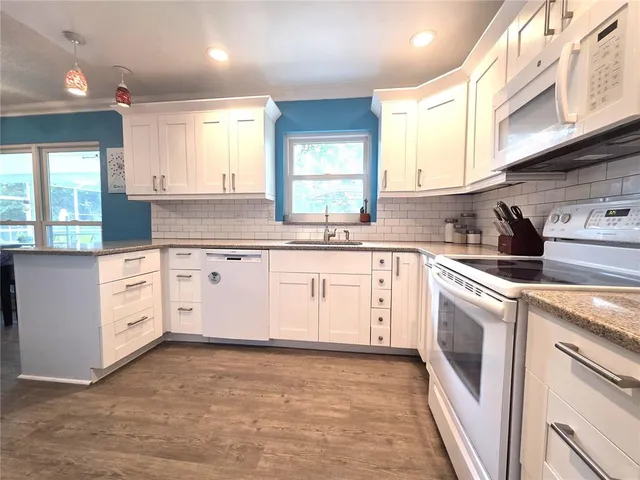 a kitchen with granite countertop white cabinets and white appliances
