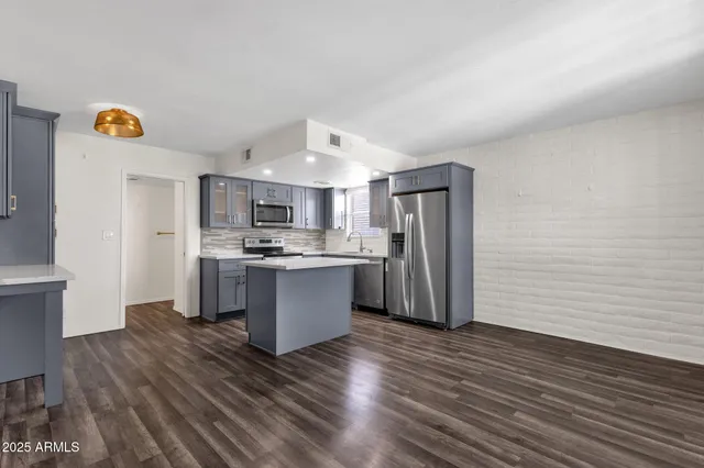 a large kitchen with stainless steel appliances granite countertop a refrigerator and a stove top oven