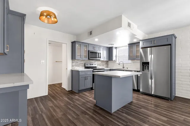 a kitchen with a refrigerator a microwave oven and a sink with wooden floor