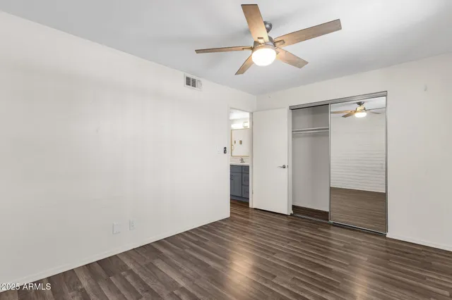 an empty room with wooden floor and ceiling fan