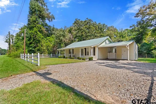 a view of a house with a yard and large tree