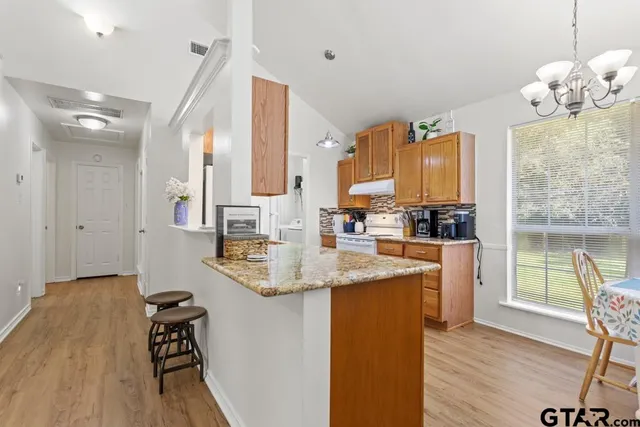 a kitchen with stainless steel appliances granite countertop a sink dishwasher and a stove with wooden floor