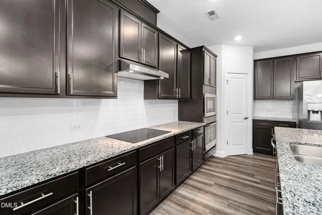 a large kitchen with stainless steel appliances a large counter top and a refrigerator