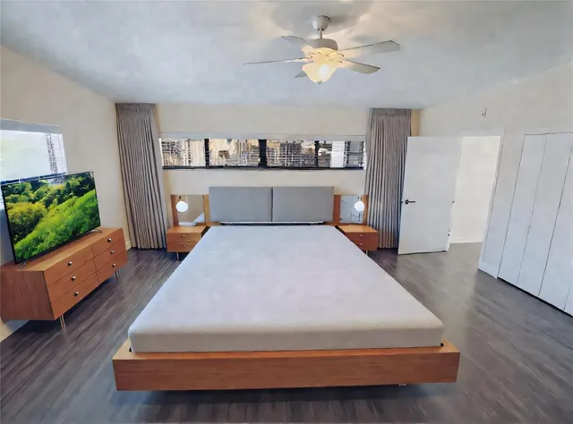 a spacious bedroom with a bed and a flat screen tv