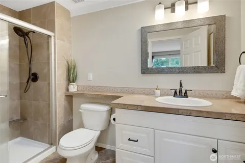 a bathroom with a granite countertop toilet sink and mirror