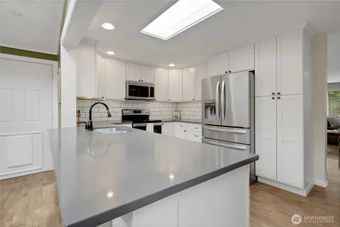 a kitchen with stainless steel appliances a refrigerator sink and microwave