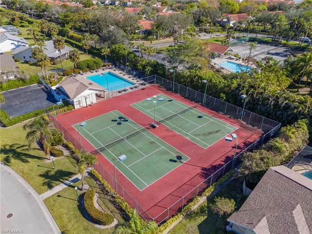 an aerial view of a tennis ground and a cars park side of the road