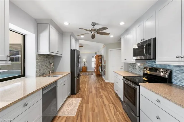a large kitchen with stainless steel appliances granite countertop a lot of counter space and wooden floor