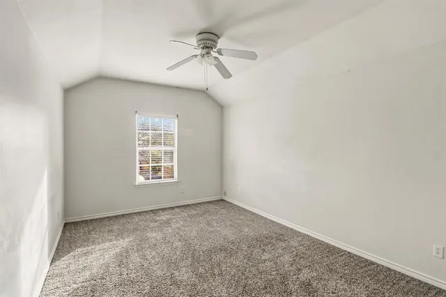 an empty room with a chandelier fan and windows