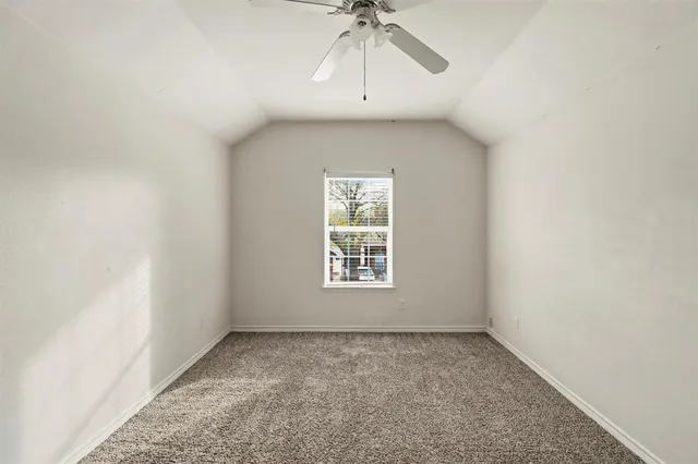 an empty room with a window and a chandelier fan