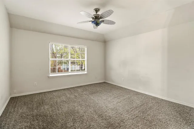 an empty room with windows and chandelier fan