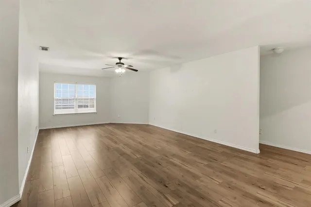a view of a room with wooden floor and a ceiling fan