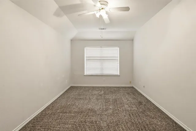 an empty room with a chandelier fan and windows