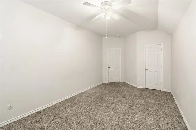 an empty room with a chandelier fan and closet