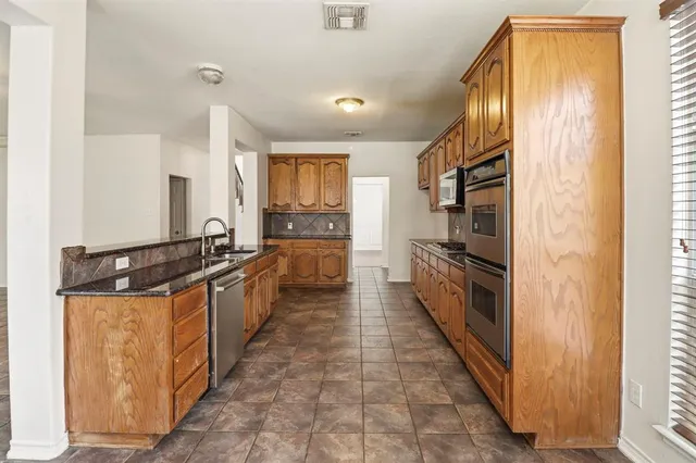 a large kitchen with stainless steel appliances a sink and cabinets