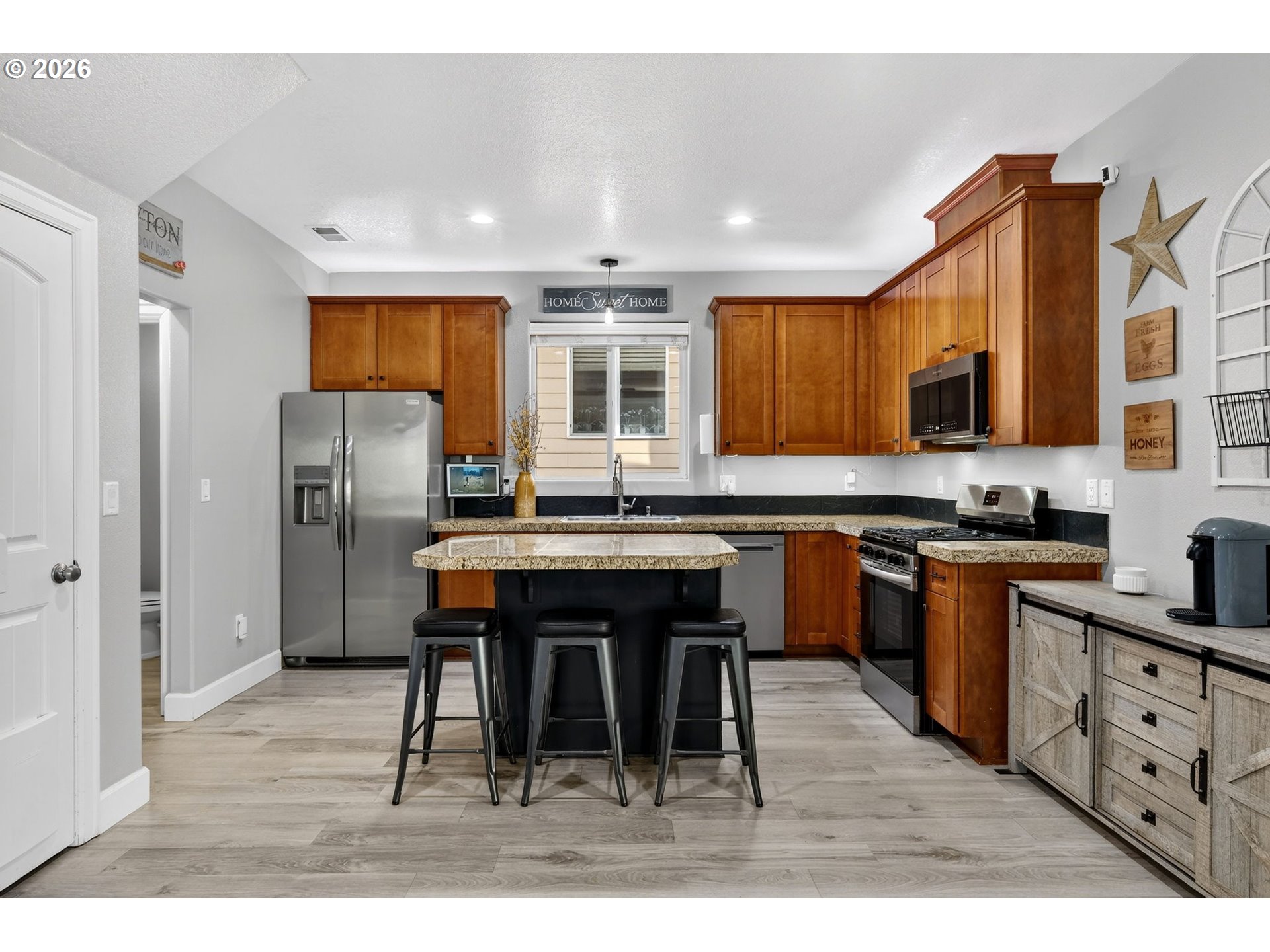 19135 Southeast Village Boulevard Sandy, OR 97055 - Photo 13 of 43 a kitchen with stainless steel appliances kitchen island granite countertop a table chairs microwave and sink