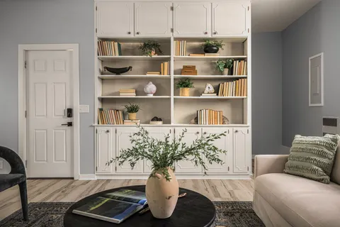 a living room with furniture cabinets and a potted plant