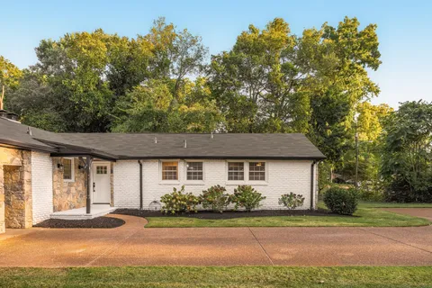 a front view of a house with a yard and trees