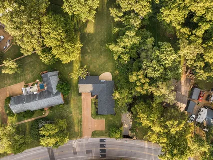 an aerial view of a house with swimming pool and large trees