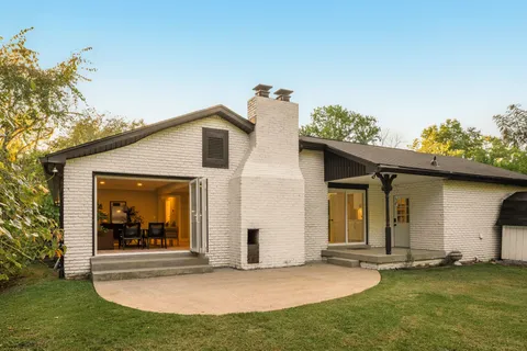 a view of a house with floor to ceiling windows and a yard